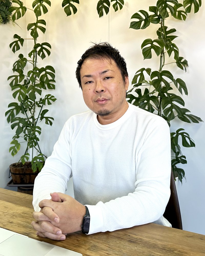Kazuyuki Imoto, founder and CEO of CCN CO., LTD., seated at a wooden desk